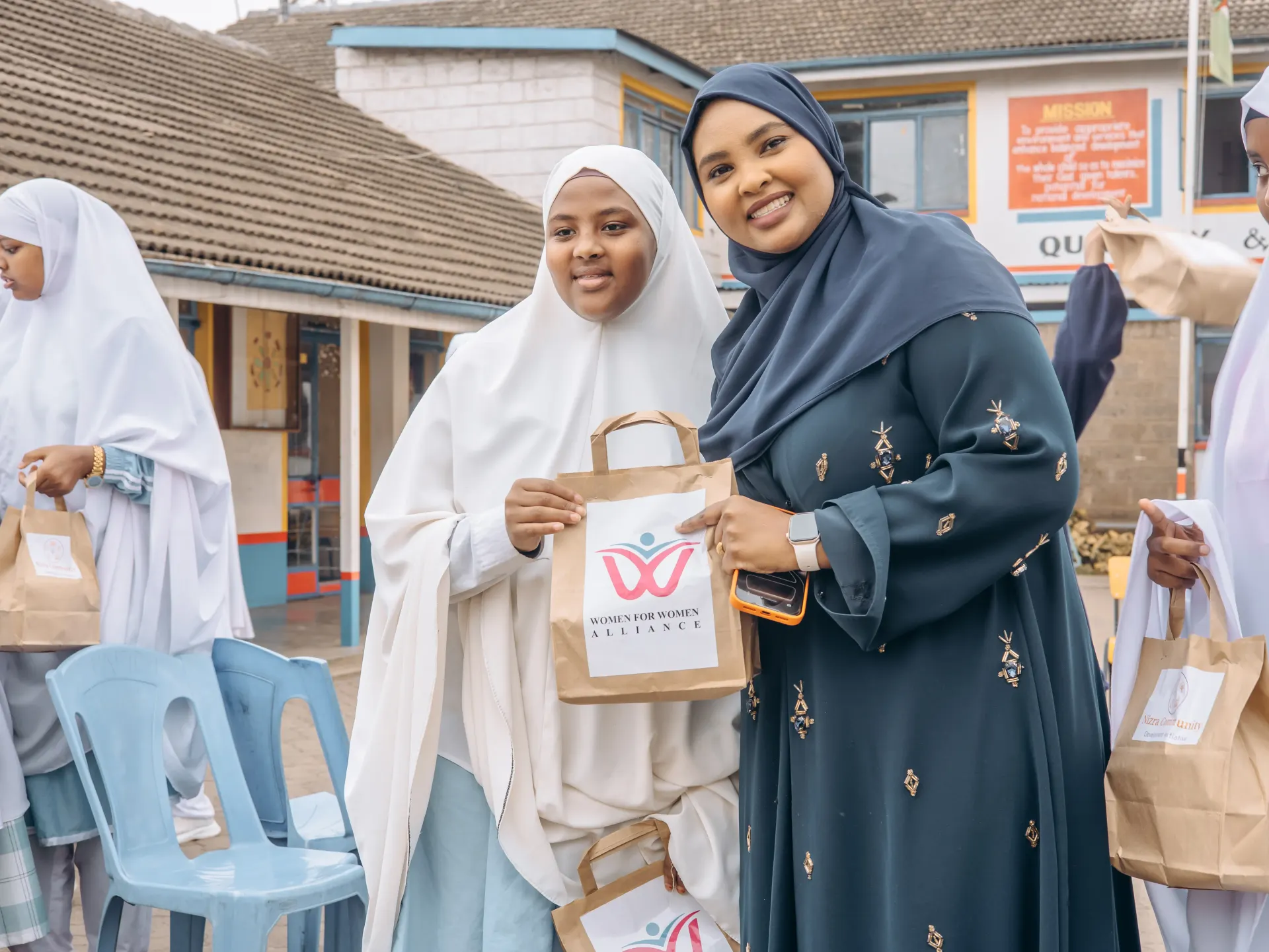Facilitators and students holding Women for Women Alliance bags after a session